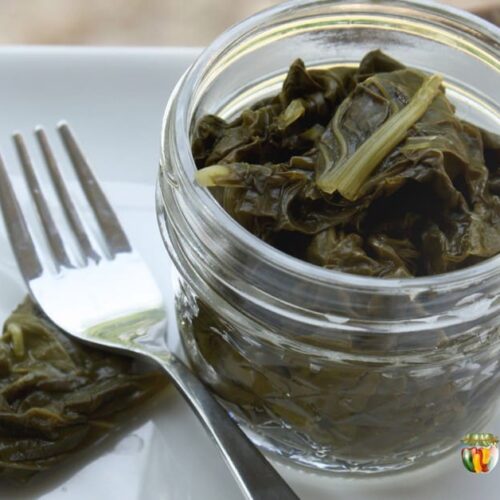 A small jar filled with cooked greens and a fork to the side.