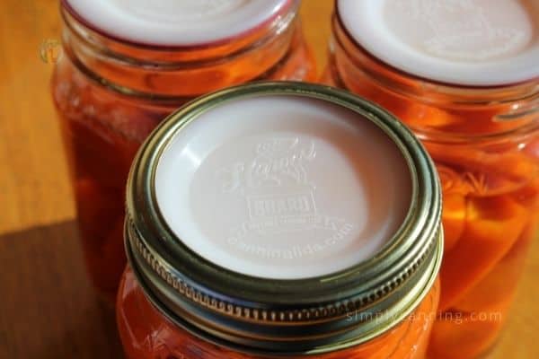 Sealed Harvest Guard lids on pint jars of carrots.
