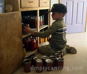 My son helping organize jars of home canned food in the kitchen cabinets.