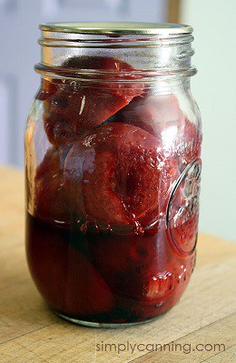 A pint jar of beets with more than half of the liquid missing from the jar.