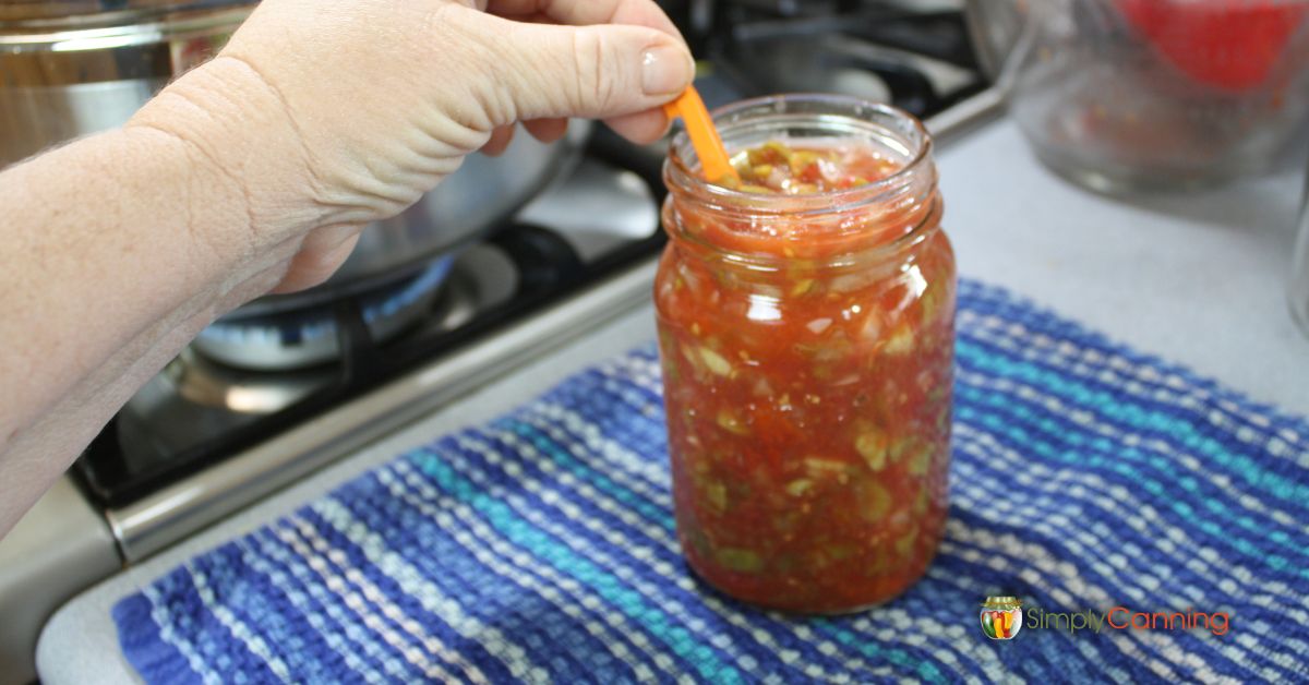 Pint jar of salsa being filled for the canner.