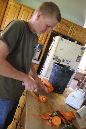 My son cutting the top off of a large carrot.