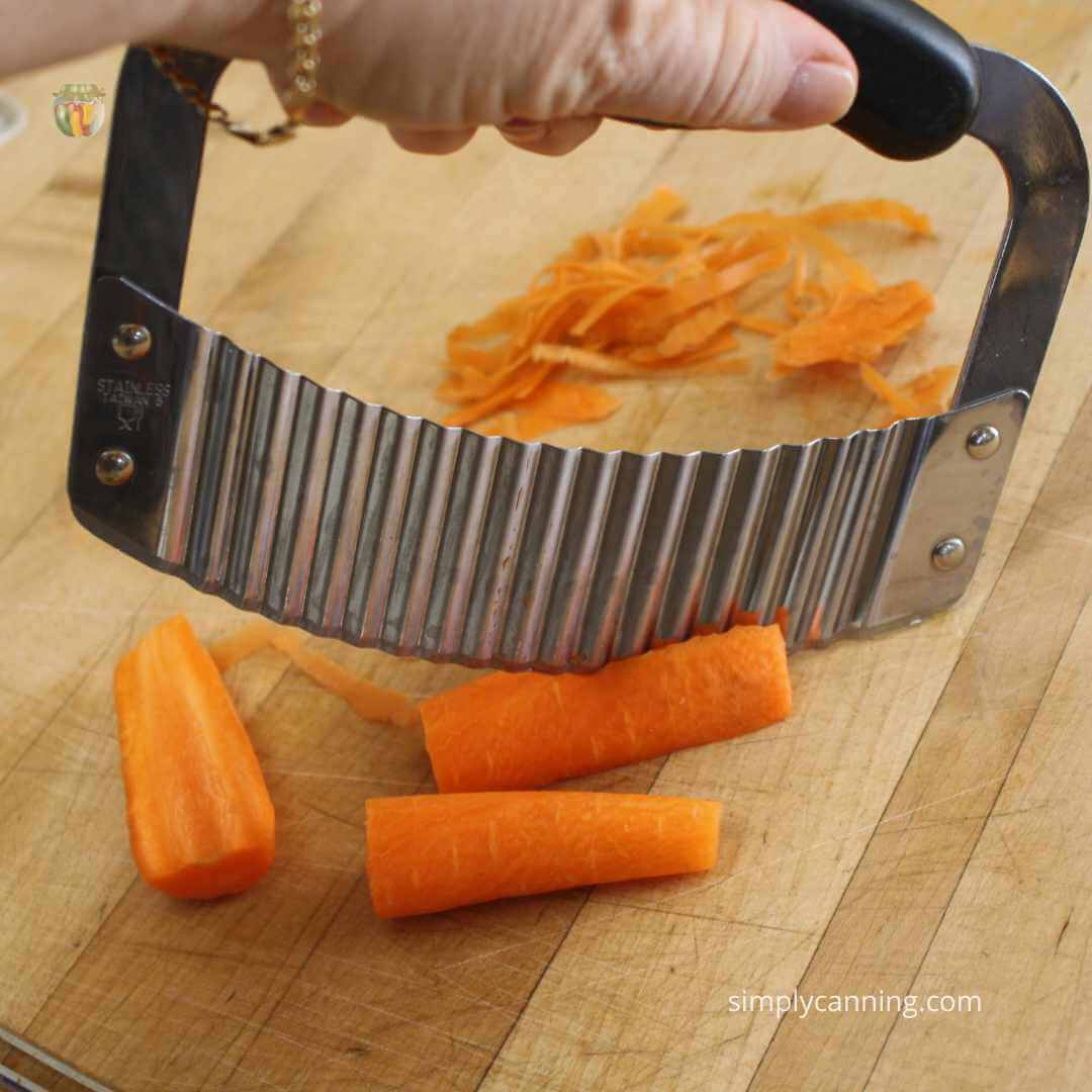 Close up of a rounded crinkle cutter, slicing through a carrot.  