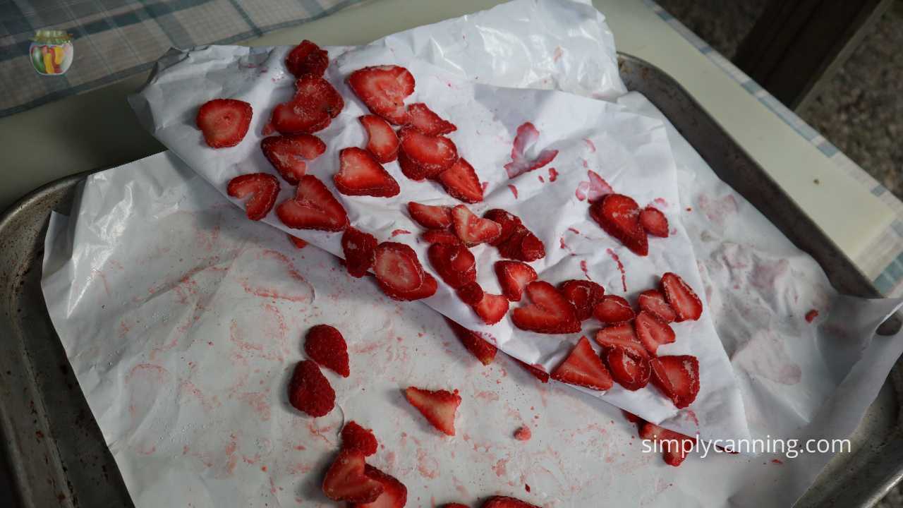 baking tray with 2 layers of strawberries, the top layer is being peeled back showing the bottom layer.