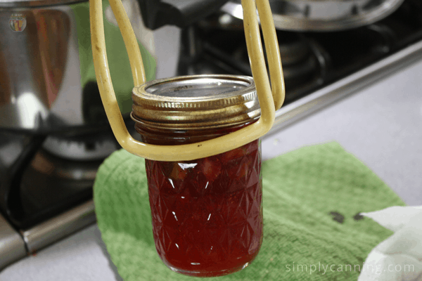 Lifting a jar of jam using a jar lifter.