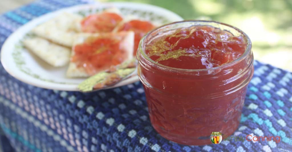 Jelly spread on crackers with an open jar of jelly to the side.