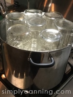 Quart canning jars turned upside down in a water bath canner.