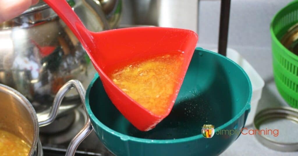 Using the Soup Saver Scoop to pour soup into a canning jar.