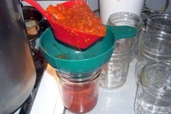 Using the Soup Saver to scoop food into a jar.