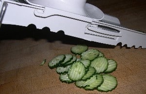 Crinkled slices of fresh cucumbers underneath the mandolin slicer.