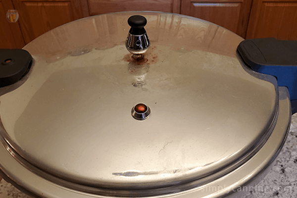 The top of the Mirro pressure canner lid with a weight placed on the vent.