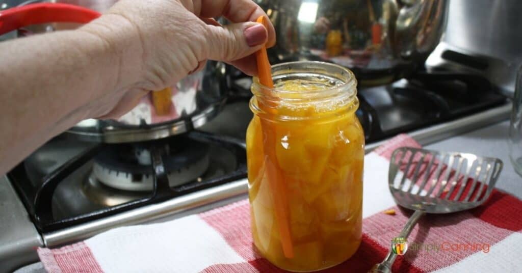 Removing bubbles from a jar of pumpkin cubes.