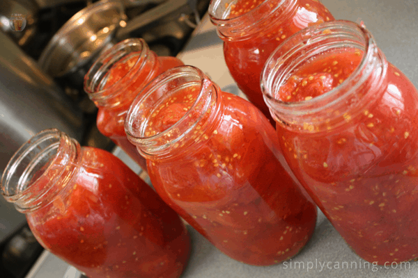 Quart canning jars filled with tomatoes and waiting for their lids.