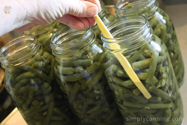 Removing bubbles from jars packed with green beans.