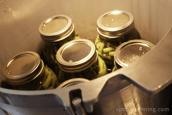 Peeking over the top of the canner to see jars of green beans inside.