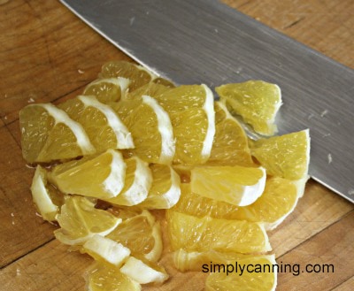 Peeled orange slices chopped into smaller pieces with a large chef knife.