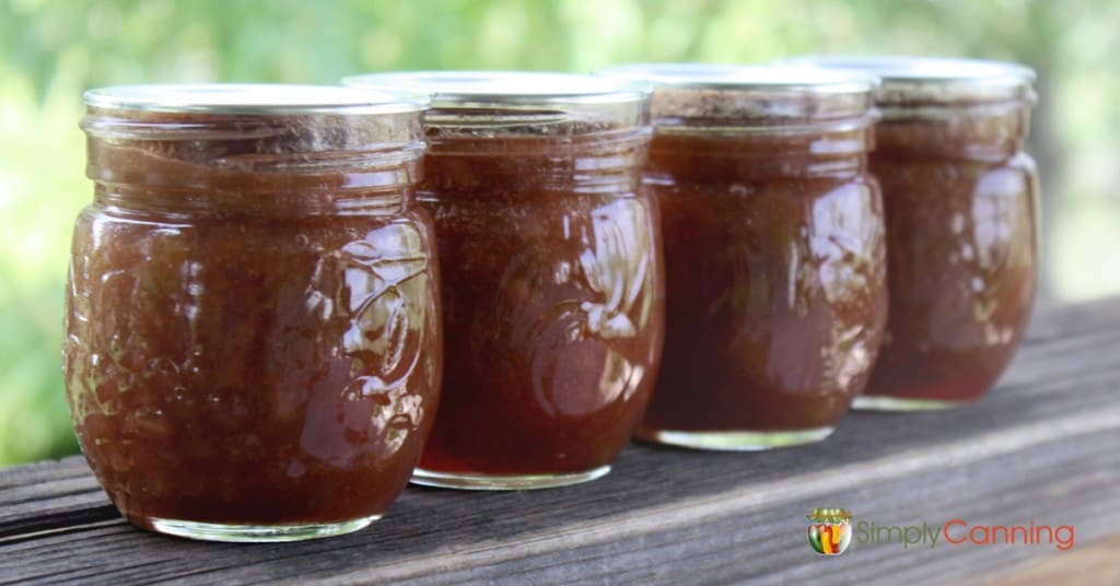 Four small jars filled with orange rhubarb jam.