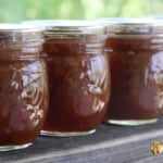 Four small jars filled with orange rhubarb jam.