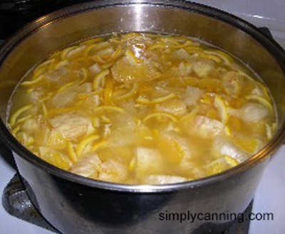Orange fruit and peels cooking in a large pot on the stove.   