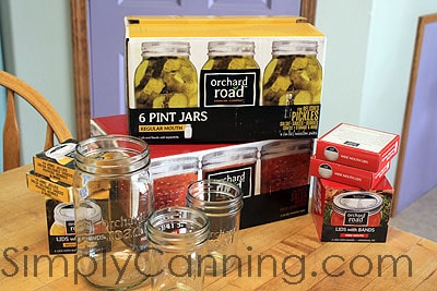 Boxes of Orchard Road canning jars and lids stacked together on the countertop with empty jars in front.