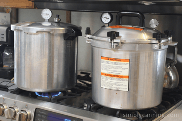 All American and Presto canners sitting next to each other on the stove.