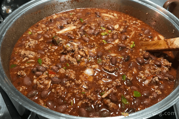 Stirring a big pot of chili or stew with a wooden spoon.