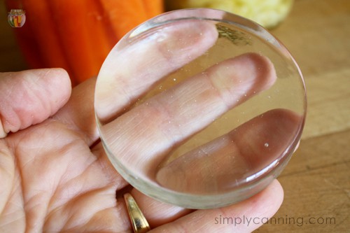 Round glass fermenting weight in hand.