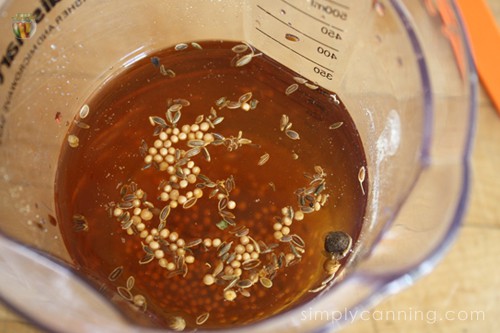 Various spices floating on the surface of a cup of a brine.