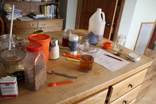 Vinegar and other pickling ingredients and supplies scattered over the butcher block countertop.