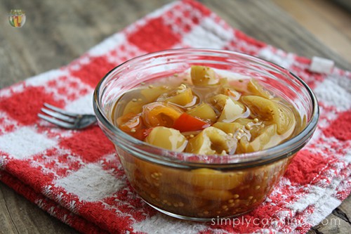 A dish of pickled pepper rings sitting on a red and white checkered napkin.