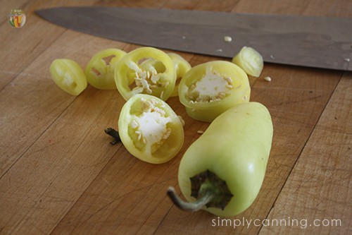 Slicing yellow peppers into rings using a large knife.