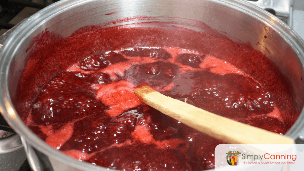 A foaming pot of red plum jam boiling away.