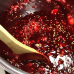 Stirring the deep red plum sauce with a wooden spoon.
