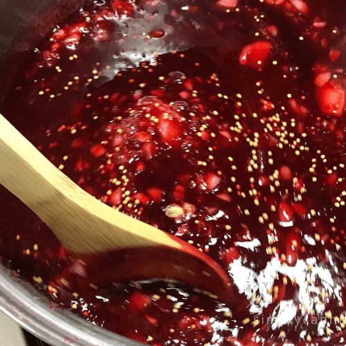 Stirring the deep red plum sauce with a wooden spoon.