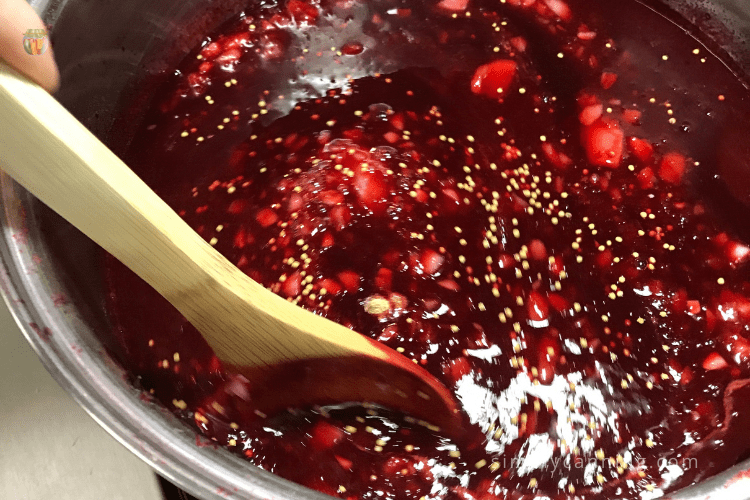 Stirring the deep red plum sauce with a wooden spoon.