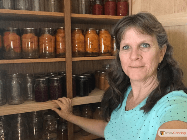 Sharon standing next to a full pantry of home canned food.