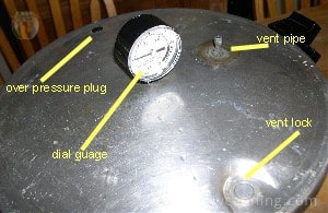 Dial gauge lid with the dial in the middle and the vent pipe off to the side.