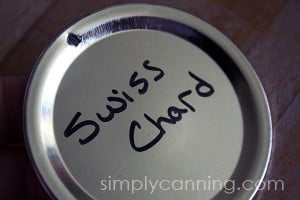 A flat canning jar lid with the words Swiss Chard written on top of it.