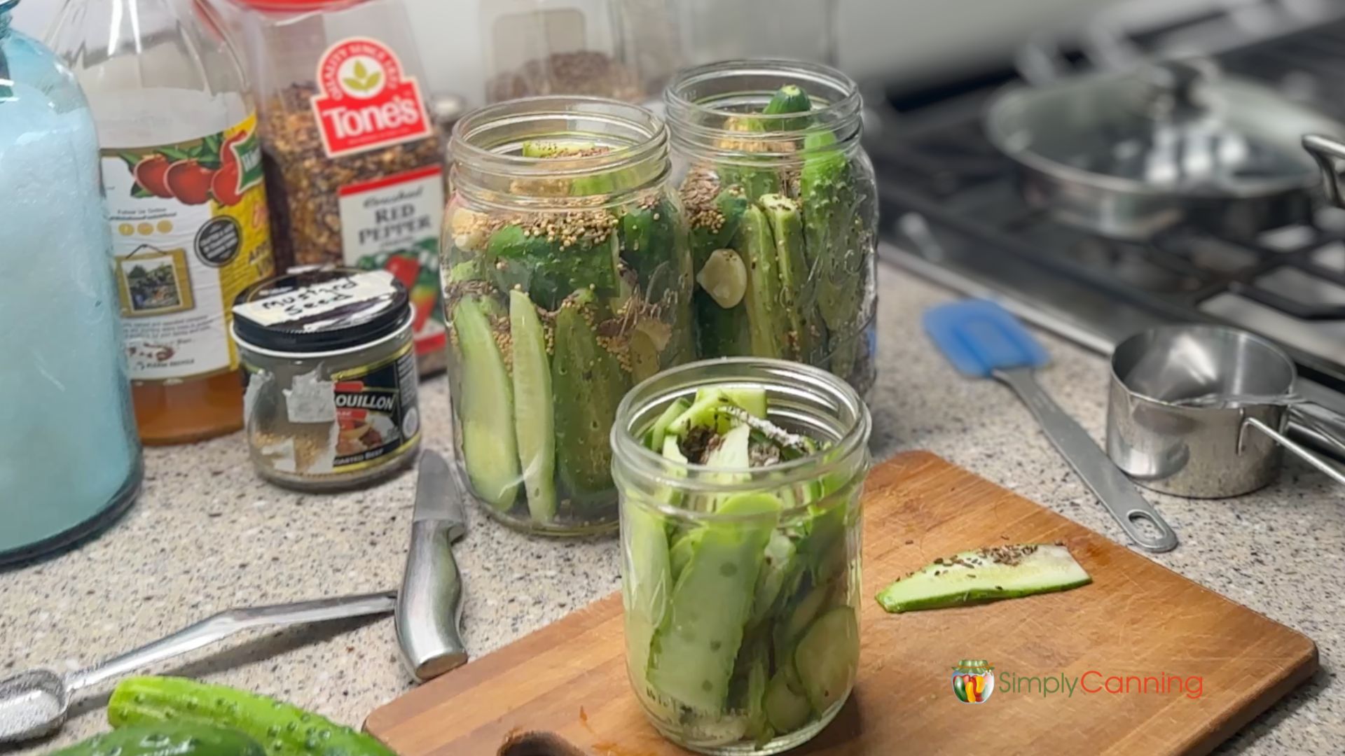 Counter with jars of cucumbers ready for spices which are scattered around.