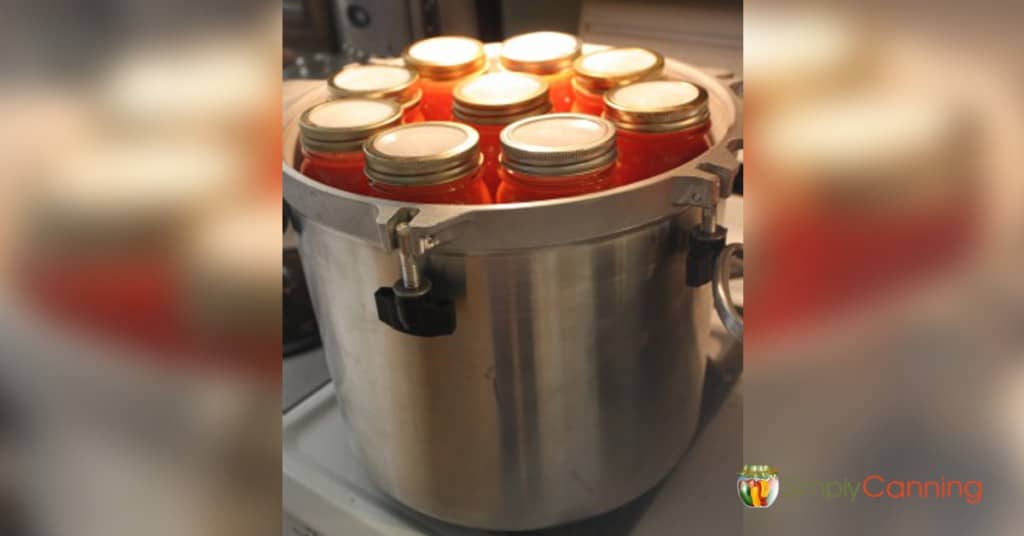 Reusable canning lids on jars that are stacked in the pressure canner.