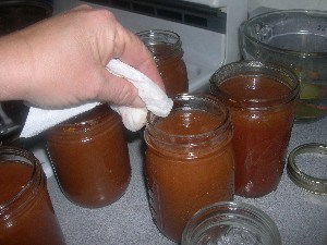 Wiping the rim of a jam jar with a wet paper towel.