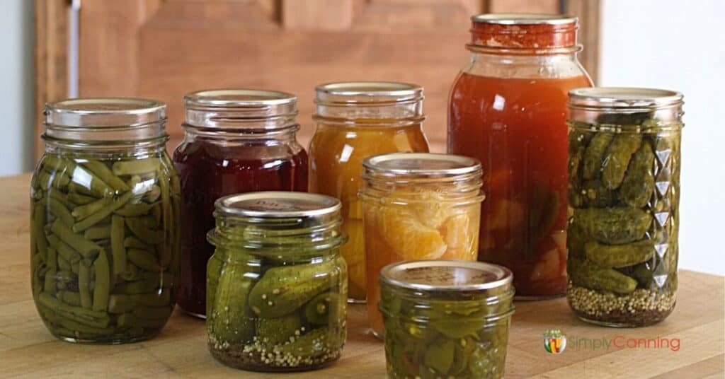 Various jars of home canned vegetables and fruits sitting on the countertop.