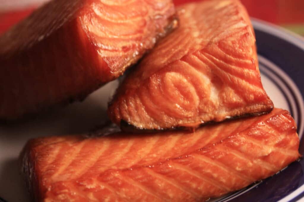 Flaky pieces of smoked salmon sitting on a plate.