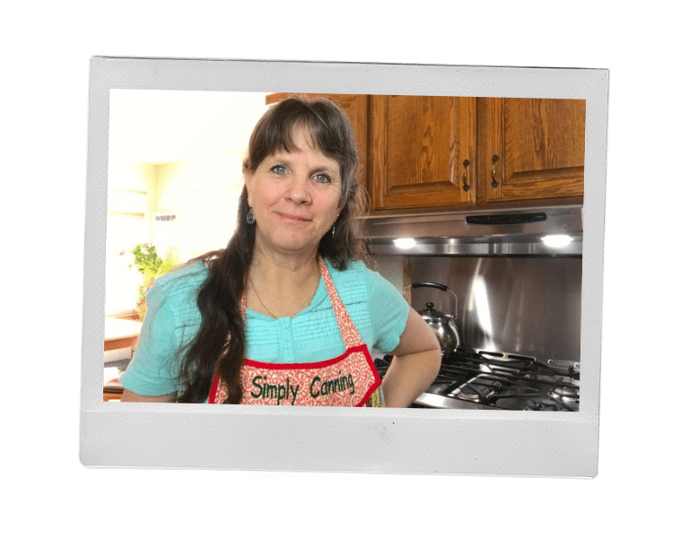 Sharon standing in her kitchen with her Simply Canning apron. 