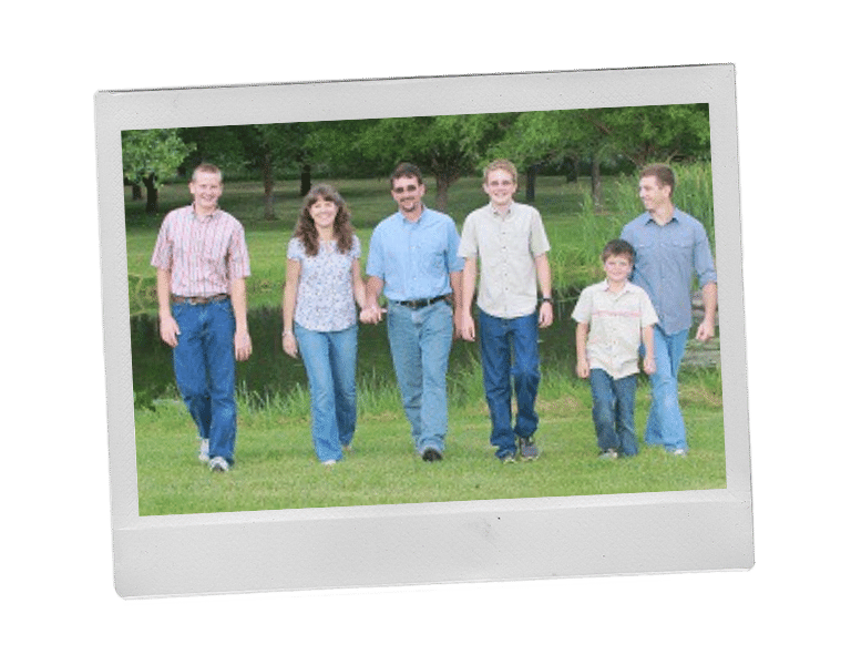 Sharon's family, husband and 4 sons walking through a field of grass toward the camera. 