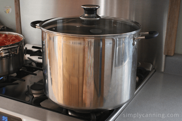 Shiny stainless steel water bath canner on the stove.