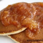 Stonefruit jam spread over golden brown pancakes on a white plate.