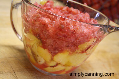 Fruit slices and chopped pulp in a large glass measuring bowl on the countertop.