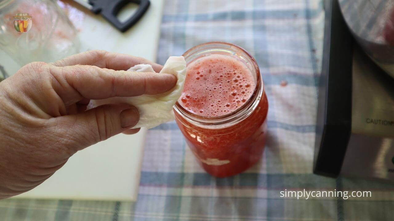 Wiping the rim of a pint jar clean before putting in the canner.  