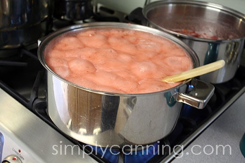 A foaming pot of strawberry jam about to boil over.